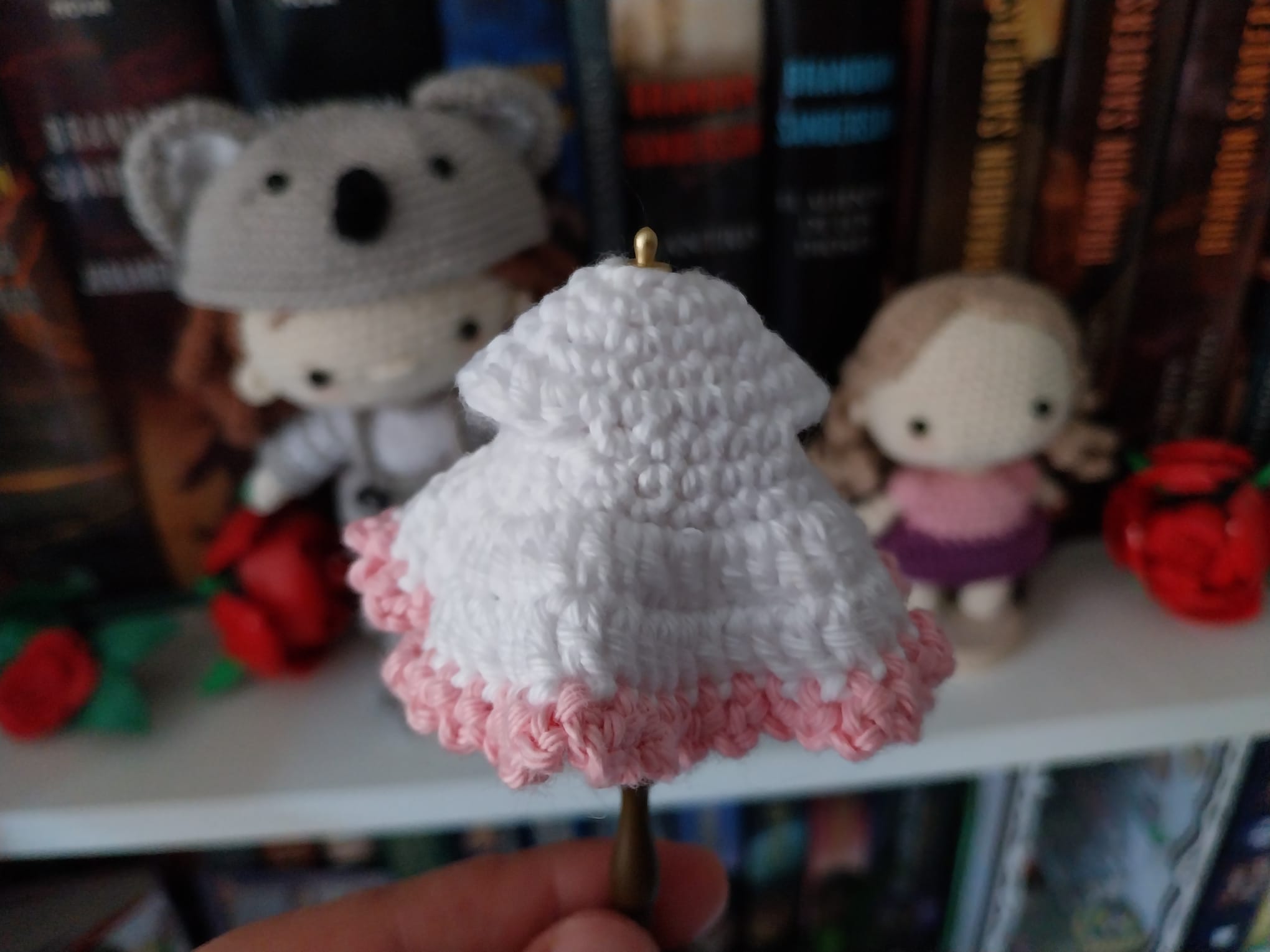 Nahansicht eines weißen gehäkelten Miniaturkleids mit rosa Bogenrand