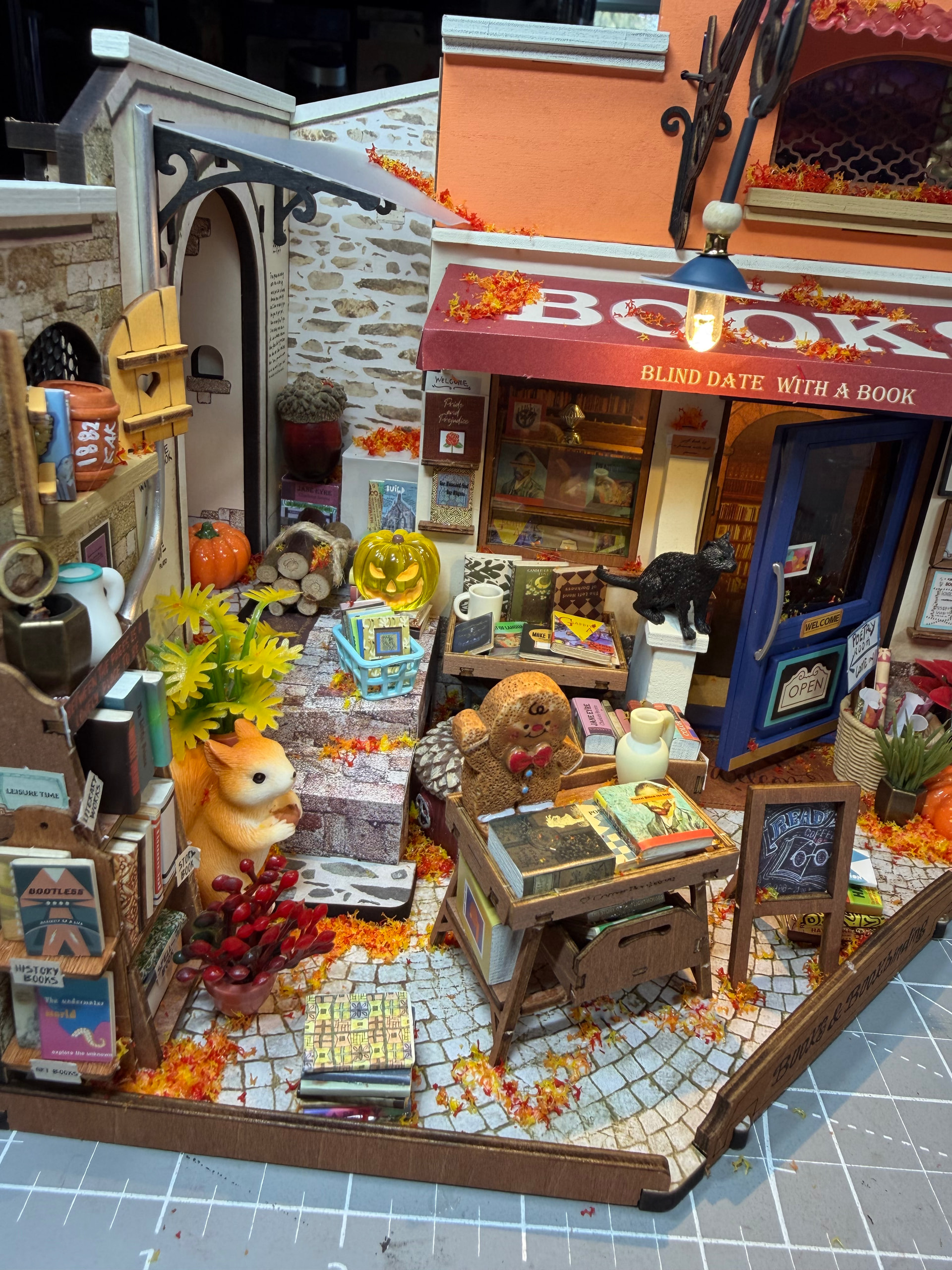 Blick von oben auf die angepasste Buchhandlung mit einer schwarzen Katze, Eichhörnchen, Büchern, Pflanzen und gefallenen Blättern