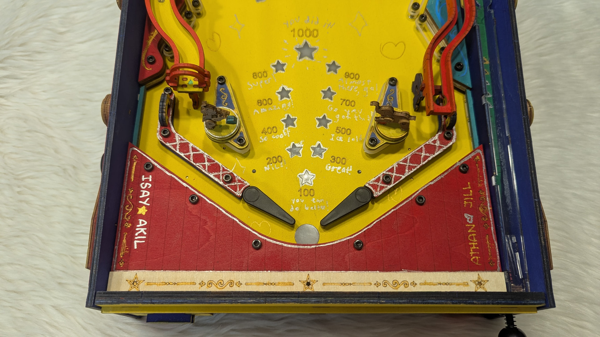 Handwritten score reactions and family names decorating the yellow and red pinball playfield