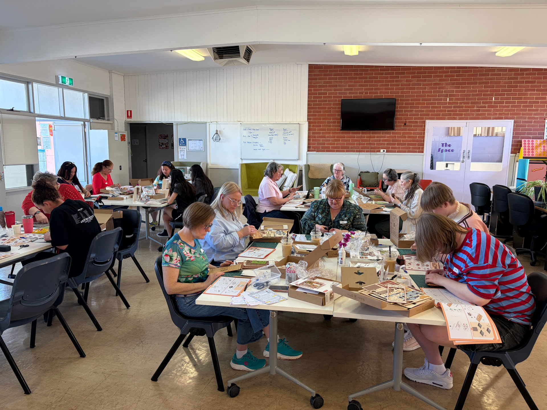 Zwanzig Bastler arbeiten an Tischen mit vielfältigen Miniatur-Kits in der Queenstown Hall