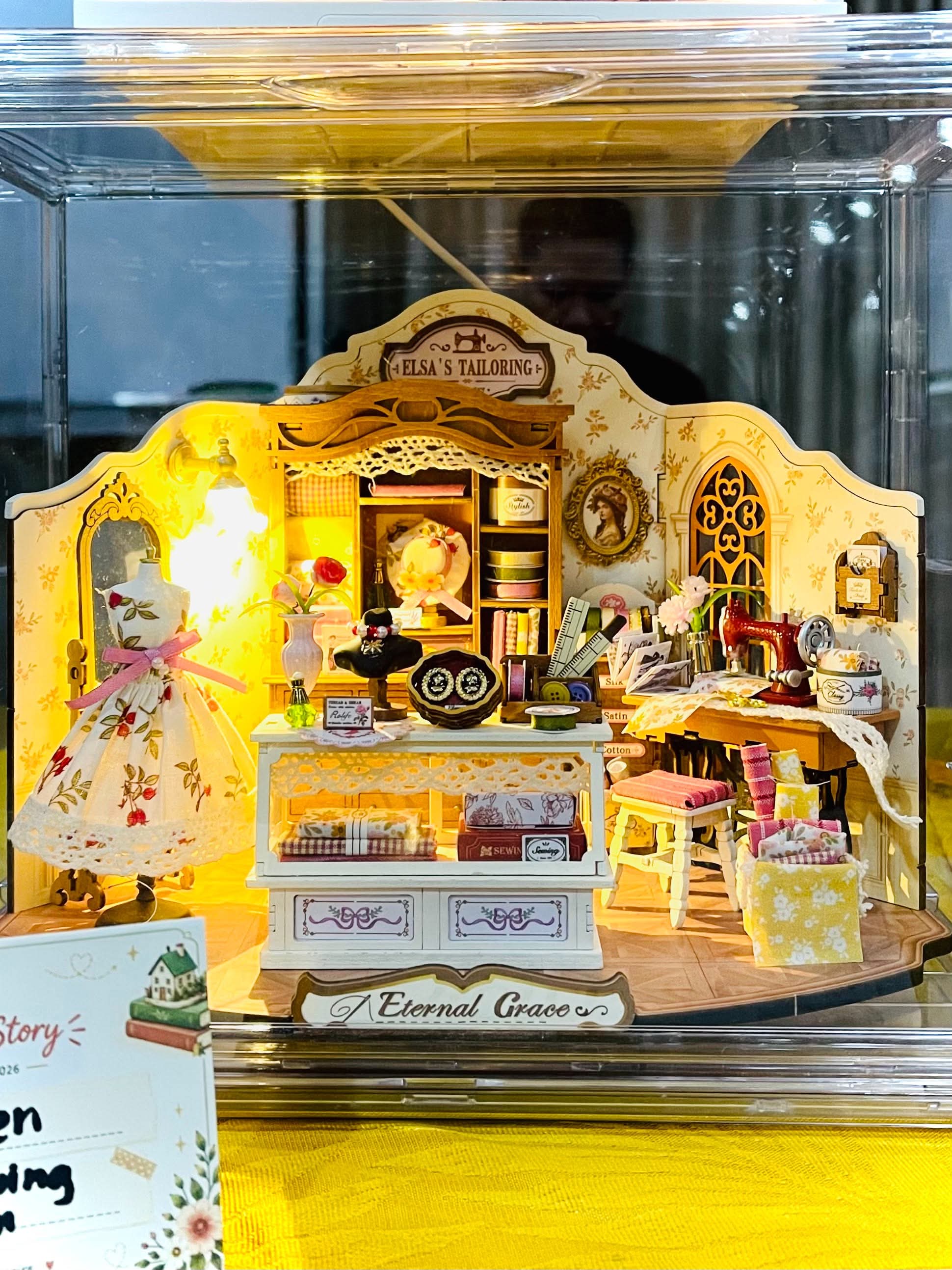 Une boutique de tailleur miniature illuminée exposée dans une vitrine transparente
